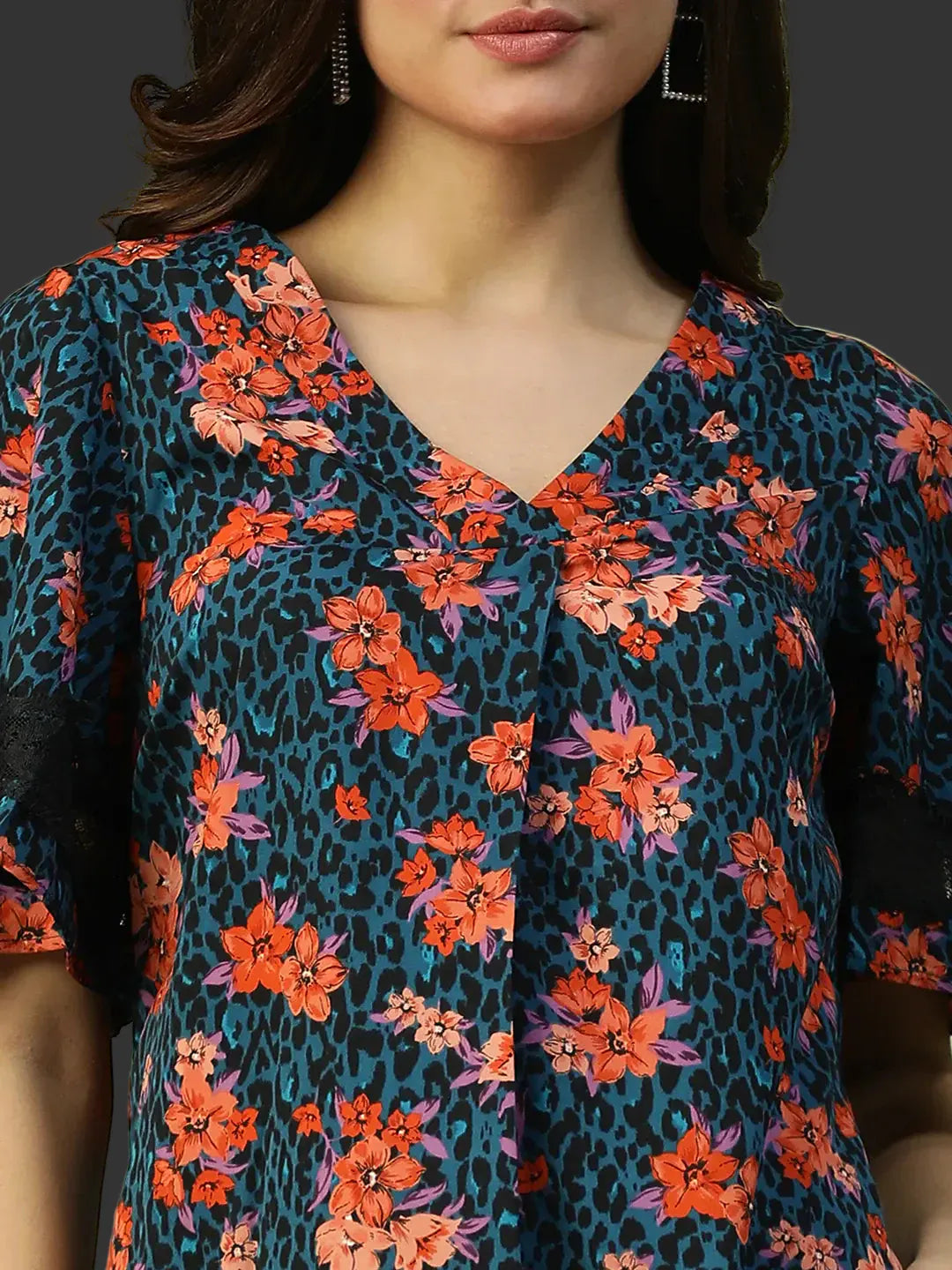 Close-up of a person wearing a floral and leopard print top with a neutral background