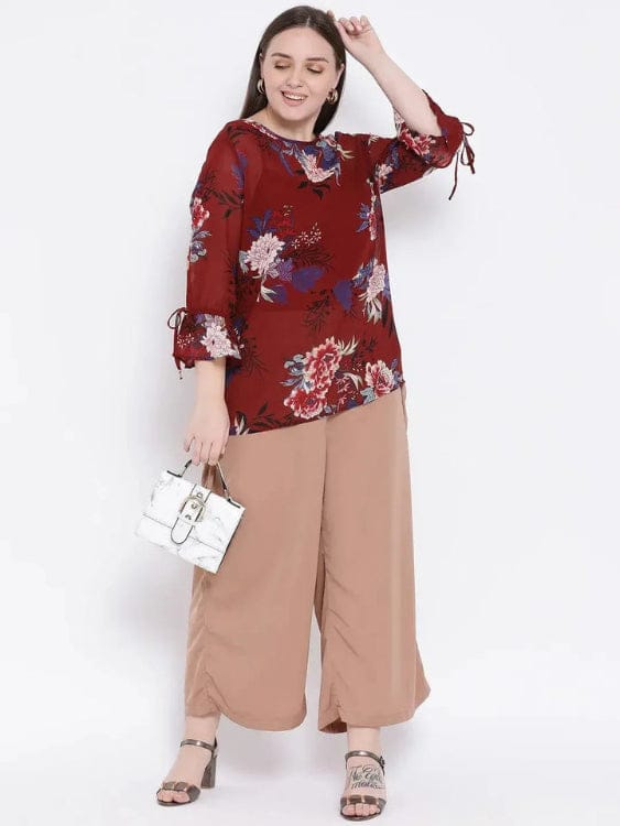 Woman wearing a red floral blouse and beige pants on a white background
